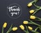 Spring flowers. `Thank you!` written in calligraphic style. Frame made of yellow tulip flowers on black background. Flat lay, to