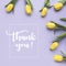 Spring flowers. `Thank you!` written in calligraphic style. Frame made of yellow tulip flowers on purple background. Flat lay, t