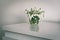 spring flowers in a vase on light table in white room - vintage