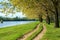 Spring forest with ground road near river, bright landscape