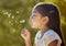 Spring, freedom and girl blowing dandelion flowers for hope, growth and environment in park. Happy, light and health