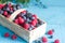 Spring fruits berries in the punnet on blue wooden boards