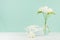 Spring gentle fresh celebration background with opened gift box and flowers in glass vase in elegant green mint menthe interior.