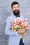 Spring gift. Bearded man hipster with flowers. Bearded man with tulip bouquet. Flower for March 8. Love date