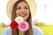 Spring girl holds flowers looking to the side outdoor. Beautiful smiling young woman with hat holding flowers in park and looks