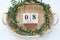 Spring green wreath of leaves rests on wooden bamboo tray. Boxwood wreath. Flat lay, top view. Wooden block calendar 8 March. Conc