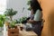 Spring hobby happy african american woman transplanting in flower pot houseplant with dirt or soil at home. Gardening