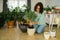Spring hobby happy young woman transplanting in flower pot houseplant with dirt or soil at home. Gardening plant and