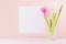 Spring hyacinth bouquet with pink and white flowers in vase with blank paper for greeting text on wood table, copy space.