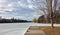 Spring ice on the Rideau River, an empty pier under a tree, a flock of geese flying in the sky with clouds