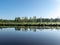 Spring landscape with a beautiful calm river, green trees and grass on the river bank, peaceful reflection in the river water