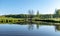 Spring landscape with a beautiful calm river, green trees and grass on the river bank, peaceful reflection in the river water