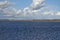 Spring landscape with a blue water lake and dramatic clouds on the blue sky. At the horizon you can see a beautiful misty white