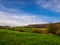 Spring landscape with a rolling meadow, forests and clouds in the sky