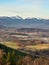 The spring landscape of Rudawy Janowickie at sunrise with the snow-covered Karkonosze Mountains in the background. Vertical view