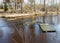 Spring landscape with a small wild river, bare trees without leaves, old board platform in a flooded river