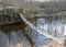 Spring landscape with a small wild river, bare trees without leaves, old wooden bridge over the river