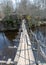 Spring landscape with a small wild river, bare trees without leaves, old wooden bridge over the river