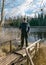 Spring landscape with a wooden footbridge on the shore of the lake, the fisherman is preparing for the fishing season, old reeds