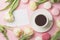 Spring morning concept. Flat-lay of cup of coffee with white flowers and macarons over light pink background, top view with space