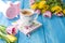 Spring morning, fragrant coffee and tulips of yellow and pink color. Donuttsy copies. Blue wooden background, pink alarm clock and
