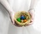 Spring nest of straw filled with colorful eggs in female hands over white background