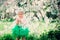 Spring portrait of cute baby girl in green skirt enjoying outdoor walk in blooming garden