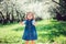 Spring portrait of cute little toddler girl in blue jeans dress walking in blooming park