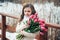 Spring portrait of thoughfull child girl with tulips bouquet on the walk