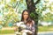 Spring portrait. Young beautiful white girl in a brown sports suit stands near blossoming branches of apple trees in the garden.