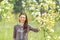 Spring portrait. Young beautiful white girl in a brown sports suit stands near blossoming branches of apple trees in the garden.