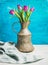 Spring purple tulips in vintage rustic copper jug, blue wall