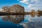 Spring river. Blue water, bare trees, clouds on blue sky.