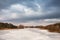 Spring rural scene. Lake under ice and snow melting. Cloudy spring day