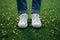 Spring selfie Feet in white sneakers on green grass background