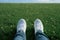 Spring selfie Feet in white sneakers on green grass background