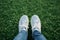 Spring selfie Feet in white sneakers on green grass background