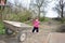 In the spring of small rural girl carries a wheelbarrow.