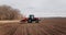 Spring sowing season. Farmer with a tractor sows corn seeds on his field. Planting corn with trailed planter