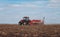 Spring sowing season. Farmer with a tractor sows corn seeds on his field. Planting corn with trailed planter