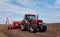 Spring sowing season. Farmer with a tractor sows corn seeds on his field. Planting corn with trailed planter