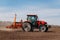 Spring sowing season. Farmer with a tractor sows corn seeds on his field. Planting corn with trailed planter. Farming seeding. The