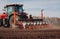 Spring sowing season. Farmer with a tractor sows corn seeds on his field. Planting corn with trailed planter. Farming seeding. The