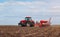 Spring sowing season . Farmer with a tractor sows corn seeds on his field. Planting corn with trailed planter. Farming seeding . T