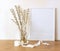 Spring still life. Blank white picture frame mockup on wooden table background. Easter composition with blooming goat willow, puss