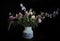 Spring still life, a bouquet of flowers of clover and herbs with spikelets in a flowerpot on a black background