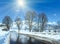 Spring sunshine and road through the alpine village in Austria with reflection of trees in thawing snow