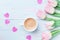 Spring tulip flowers and cup of coffee on pastel blue table top view. Beautiful spring breakfast on Mothers or Womans day.Flat lay