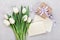 Spring tulip flowers, gift box and paper card on gray stone table from above in flat lay style. Greeting for Womens or Mothers Day