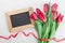 Spring tulip flowers with ribbon and wooden frame with empty space for text on gray stone table top view in flat lay style.